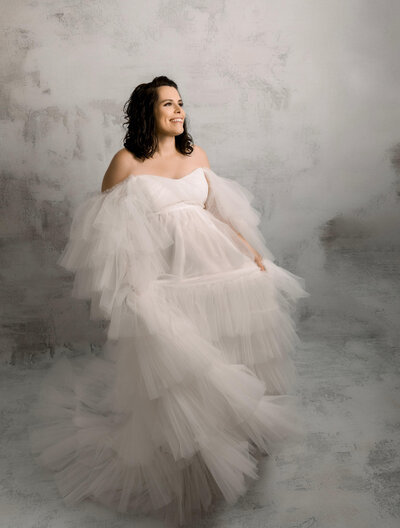 Maternity photo of a woman in a white dress in an Erie Pa photography studio