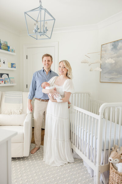 Parents holding newborn while standing in his blue and white nursery. - Newborn Photography Greenville SC