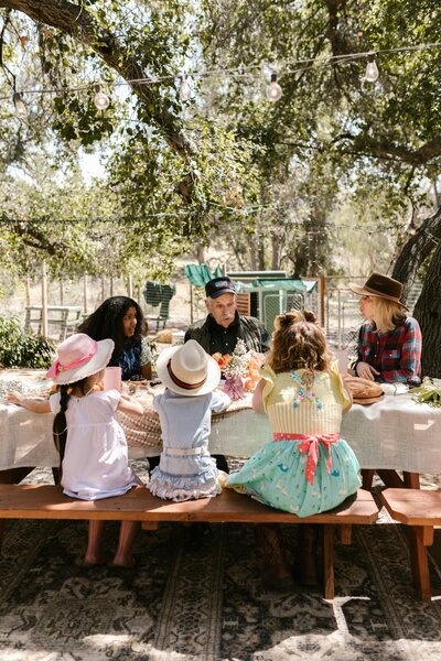 Diverse group of adults and children gathered at picnic table | Rooted Within parent guidance and support Santa Barbara