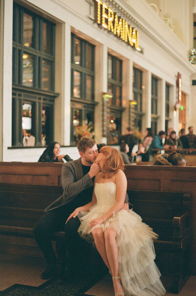 Couple kissing during their modern engagement session inside the terminal at Union Station Denver captured with film photography