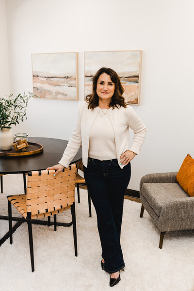 Dena smiling while standing in her beautiful therapy office