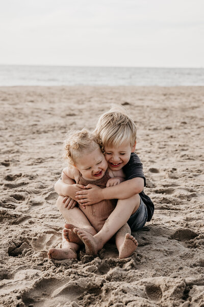 Knuffelende kindjes op het strand tijdens zonsondergang..