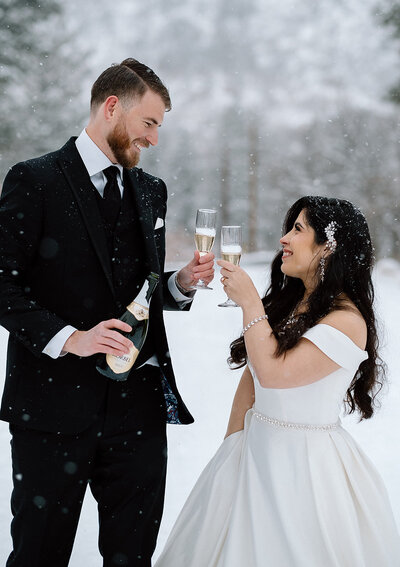 bride and groom toast with champagne after their snowy wedding ceremony in Colorado