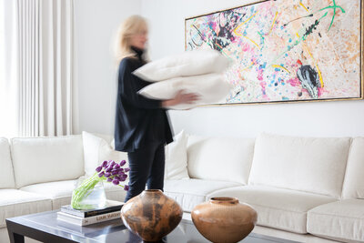 Andi Morse of Morse Design, an Alpharetta Interior Designer, arranges pillows in the great room of the Buckhead Empty Nesters project