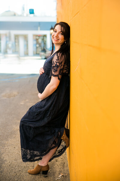 Photo of expecting mother leaning against a wall holding belly | Maine Maternity Photographer