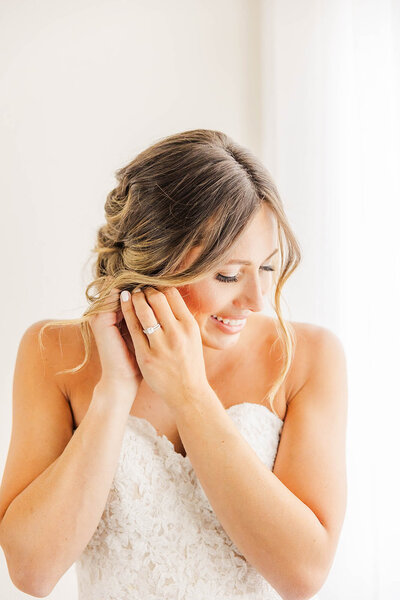 Bride putting on her earrings getting ready for her wedding day at the Arrowhead Golf Course in Littleton, Colorado. 