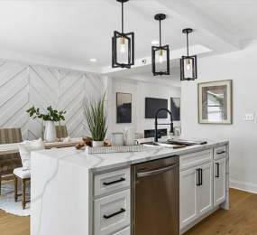Stunning open-concept kitchen with quartz waterfall island, modern pendant lighting, stainless steel appliances, and custom chevron accent wall—perfect blend of style and functionality for today’s home.