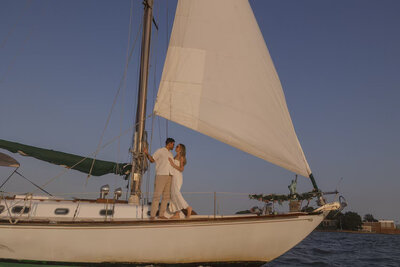 Elegant couple standing on a sailboat on the Hudson River, gazing at each other.