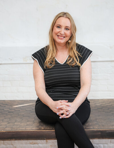 Shannon Russell business coach for women sitting on a table smiling. Second Act Success