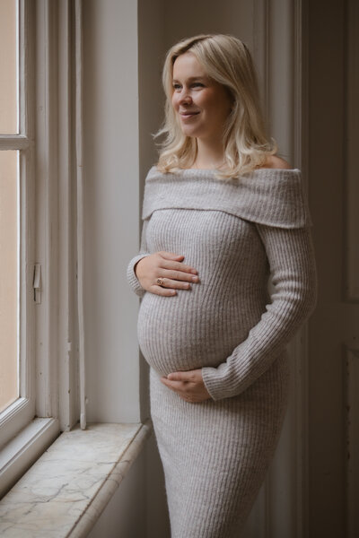 Een zwangere vrouw houdt liefdevol haar buik vast, stralend van geluk en verwachting.