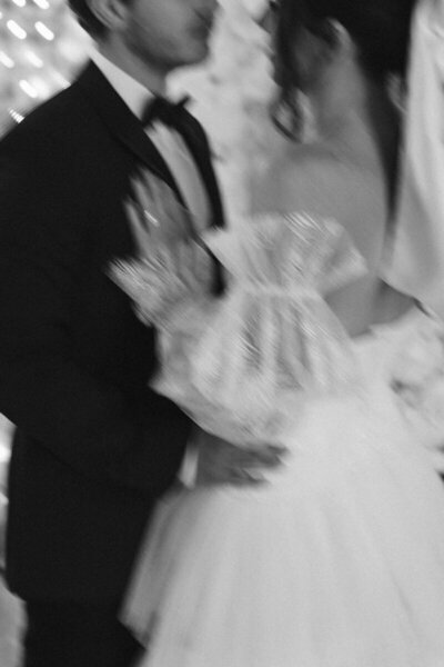 A beautifully blurred shot of a couple sharing their first kiss on their wedding day, captured in an artistic and romantic style.