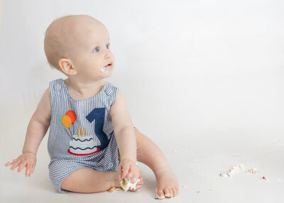 A baby on a white background at his first birthday milestone photoshoot in Allison Reilly's Union County, NJ photo studio.