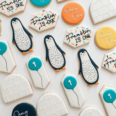 Cutout cookies decorated to look like penguins, blue balloons, igloos, and some that say Franklin Is One.