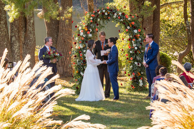 Two people holding hands and standing up as they say their vows 