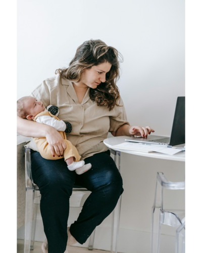 A mother holding her new born while checking something on the computer