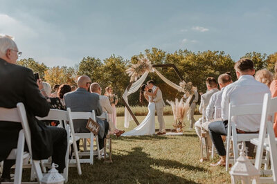 Couple sharing their first kiss under a rustic outdoor arch