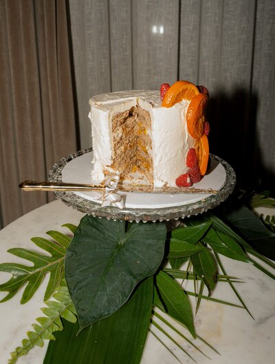 Partially sliced wedding cake with orange florals captured at a reception, photographed in a candid, documentary style by Chicago wedding photographer Abe Fernandez
