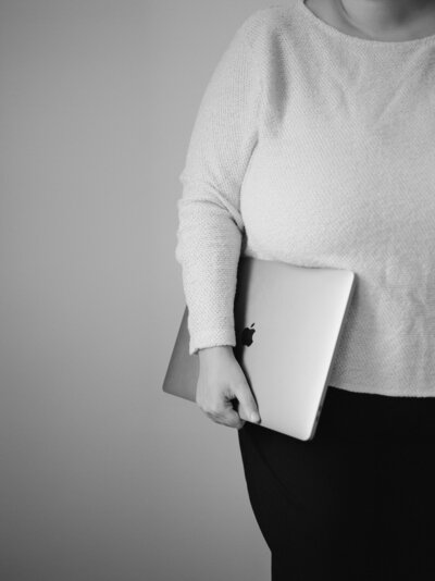woman in white sweater holds folded macbook at ALEO Detroit brand photoshoot, film brand photography