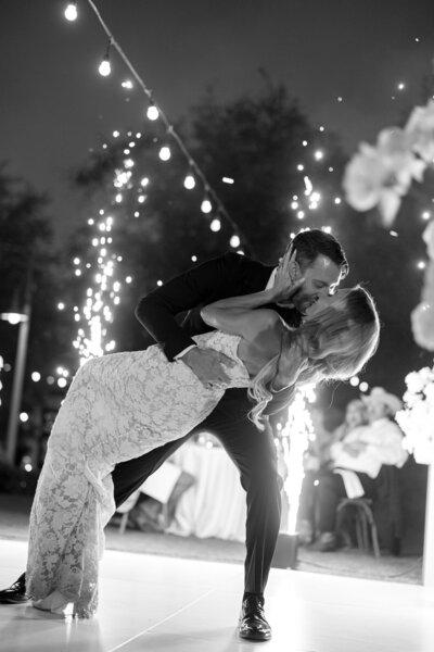 Groom dips bride during first dance with sparklers