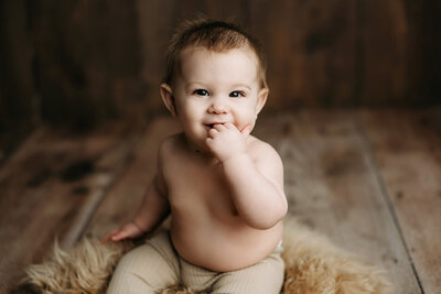 Colorado six month old sitting with his hands in his mouth