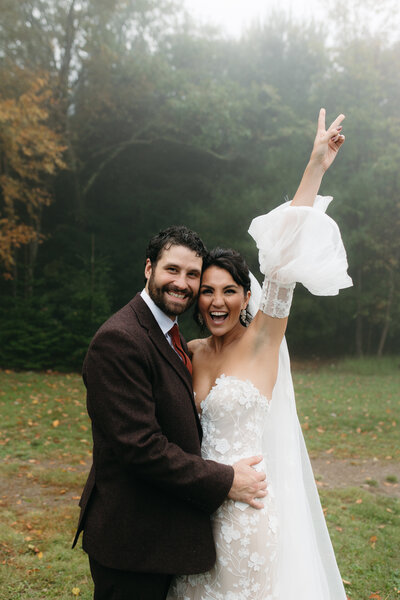 A fun and candid photo of the bride throwing a peace sign during her couple photos. The groom is by her side and laughing candidly. 