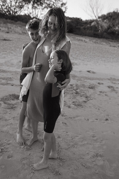 A mom and her two boys in the sand dunes at cabarita beach at sunset 