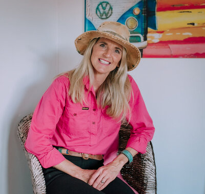 courtney brown sitting in office chair, pink shirt and hat