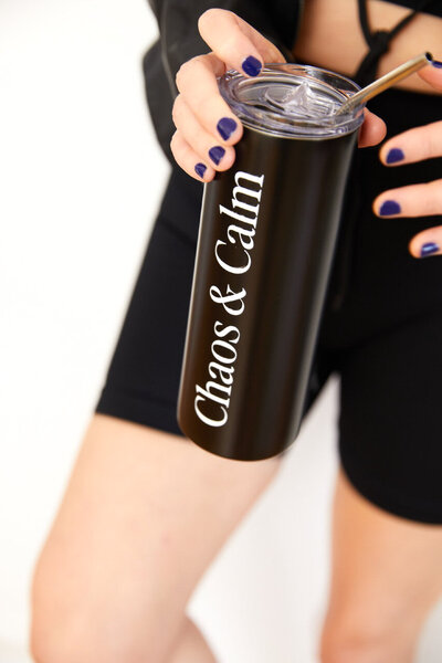 Georgiana holding the black and white Chaos & Calm stainless steel tumbler