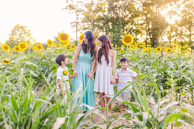 Adorable mom with children pose in a sunflower field for motherhood session in Brandon, MS.