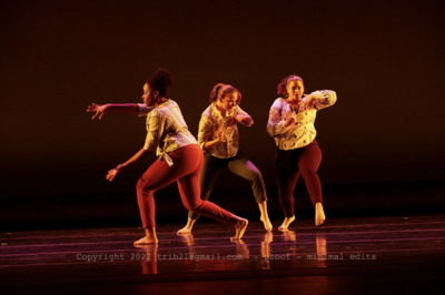 Three woman in modern dance positions on stage at a recital