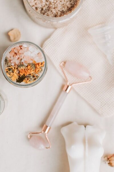 A table displaying a jar of herbs, a jar of soap, and a jar of flowers, arranged neatly for a decorative effect.