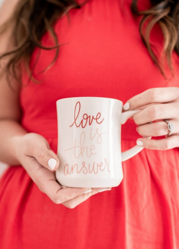 woman holding a mug with the words love is the answer