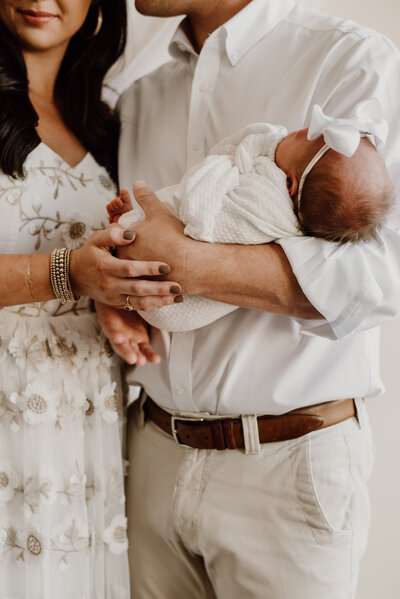 Newborn photo of baby girl being held by mom and dad in studio in Annapolis Maryland.
