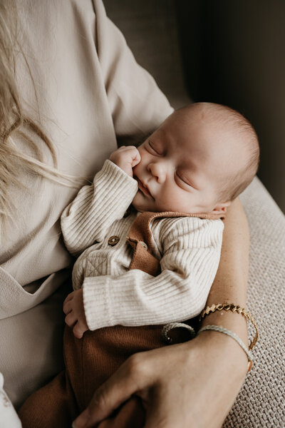 Baby ligt te slapen bij moeder in de armen newbornfotografie in IJsselstein.