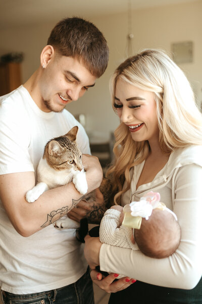 Photo of new mom and dad holding newborn baby and their cat during in home newborn session with Alexis Adkins Photography in Firestone Colorado