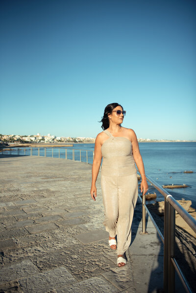 Portrait of Asmahan, a strategic online business manager, sitting confidently in a neutral dress against a stone backdrop