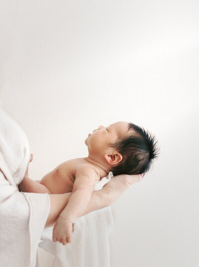 Mom holding baby against white studio backdrop, taken by San Francisco Bay Area photographer Laurel Smith.