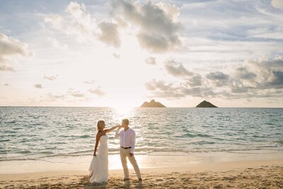 A couple pose together on the beach at sunset.