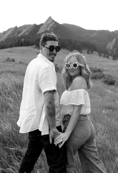 Fun, personality-filled engagement photo with couple wearing retro flower sunglasses at Chautauqua Park in Boulder