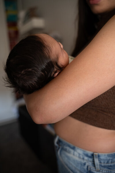 Image of mother cradling their newborn in a clean aesthetic bedroom.