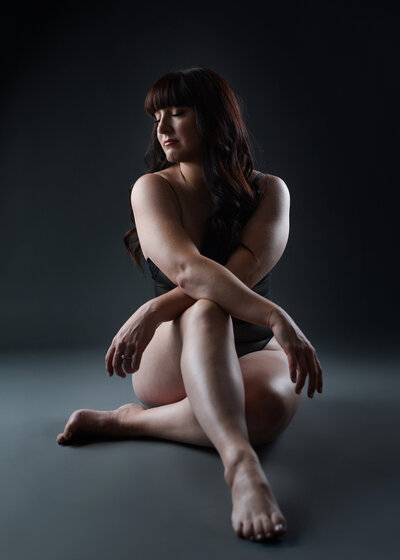 Woman sitting on floor with eyes closed and head to the side with dramatic lighting