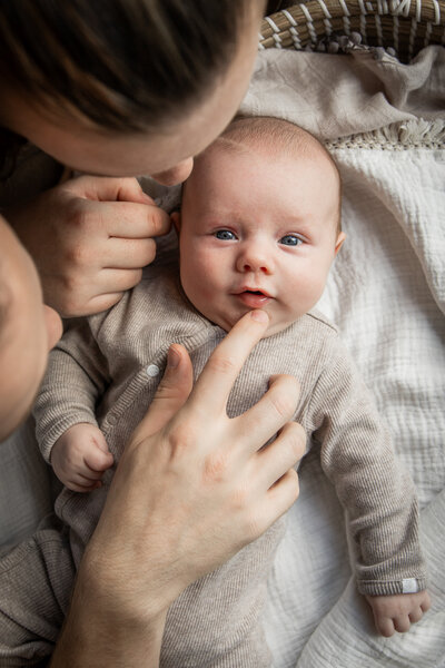 Baby ligt op een kleedje met vader en moeder erbij  –newbornfotografie door Lianne Kastelein in regio Alphen aan den Rijn