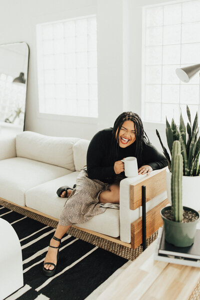 Headshot of wedding photographer Katt Leon, smiling and laughing on a couch