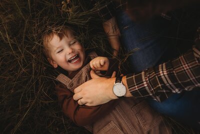 toddler son laughing while being tickled during a family golden hour photoshoot in the woodlands texas