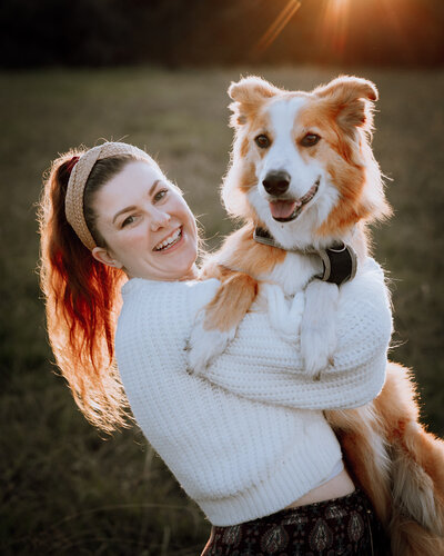 Girl in a white jumper holding a sable border collie dog