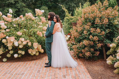 A couple holds one another in front of florals