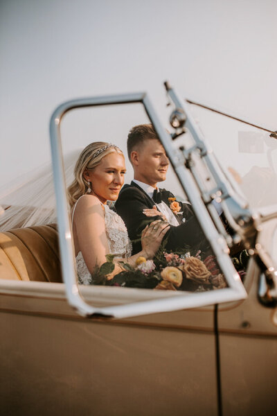 bride and groom driving in vintage car