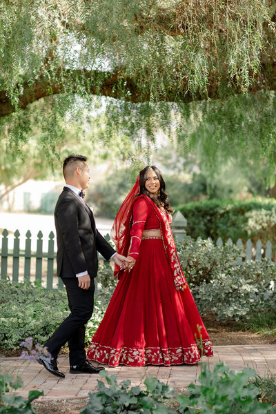 Young Indian and Asian couple getting married at Maravilla Gardens in Camarillo California in a red dress and black tux 