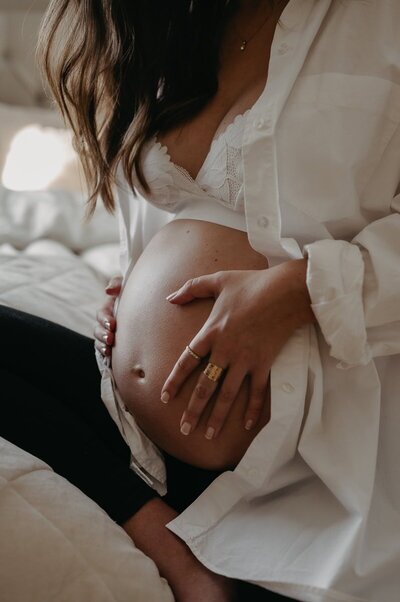 Gravid kvinna sitter och håller sin mage med båda händerna.