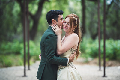 Groom kisses his bride’s cheek during an emotional outdoor ceremony, planned with heart and ease by a wedding planner in Austin, TX.